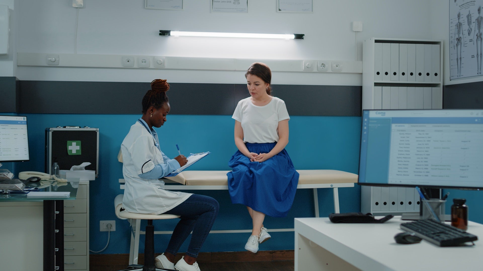 doctor sitting on stool while checking patient