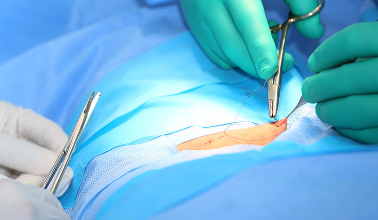 Macro shot of doctors making a suture in operation room