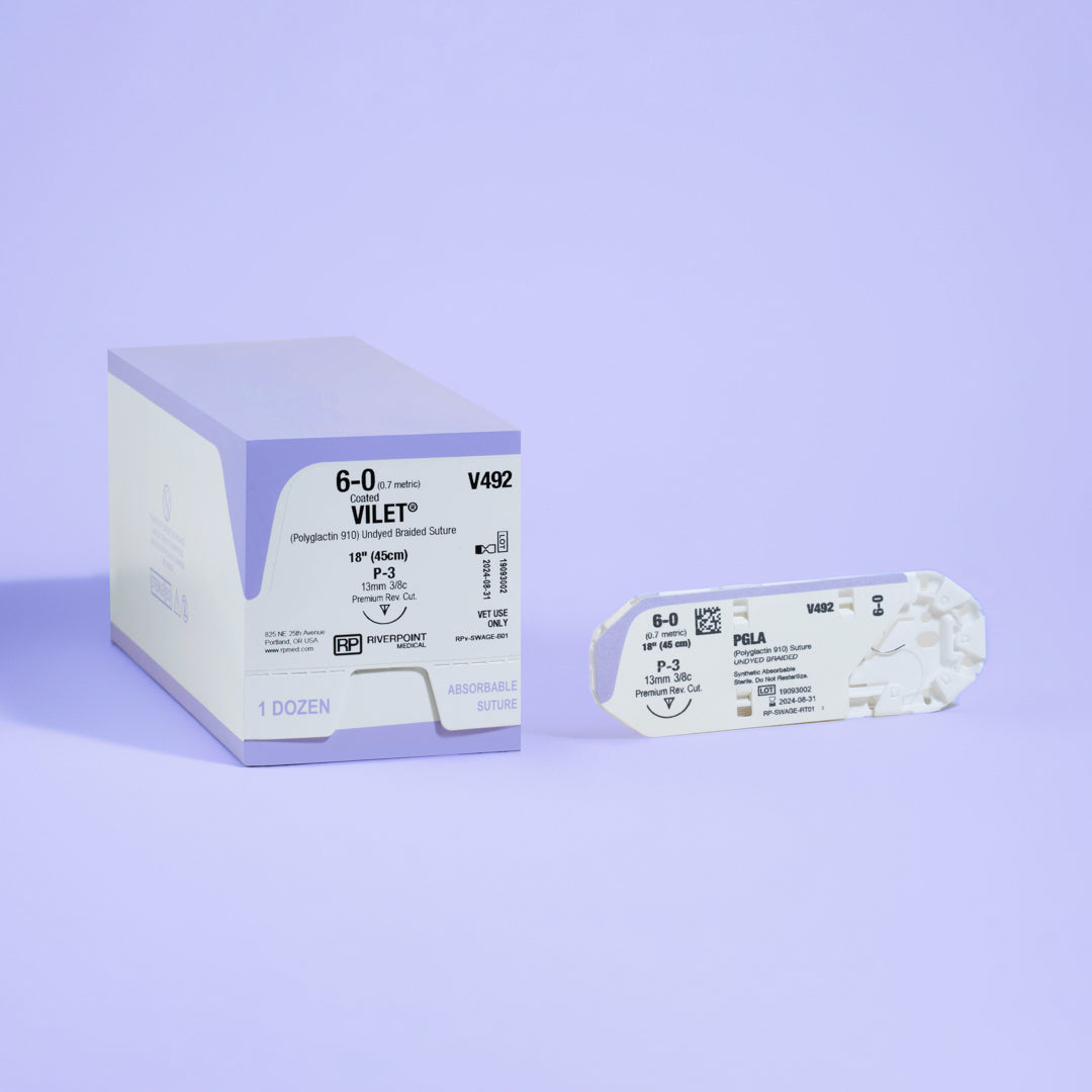 Photograph featuring the 6-0 VILET® Undyed Braided 18" P-3 Needle (V492) box next to its open sterile packaging, illustrating the product details and its readiness for use in specialized veterinary surgeries, manufactured by Riverpoint Medical.